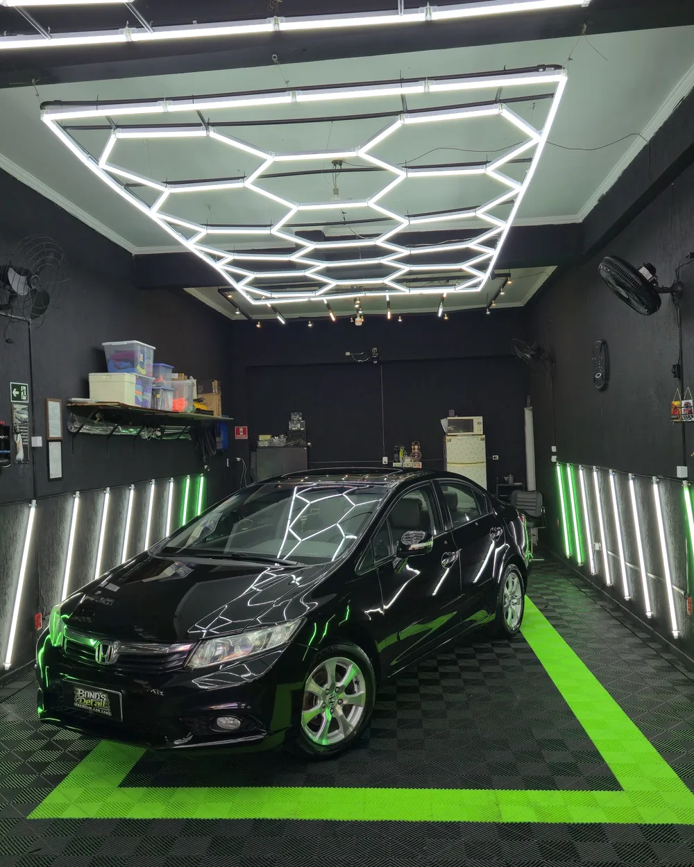 Sedã preto com pintura espelhada sob o teto de LED da Bond's